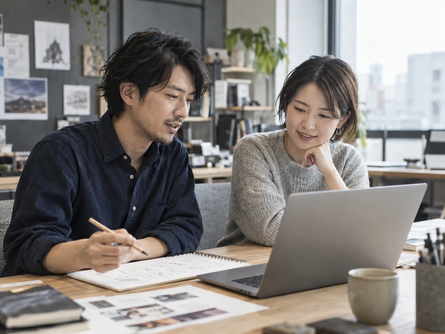 パソコンを見ながらアイデアを話し合う二人の仮イメージ写真